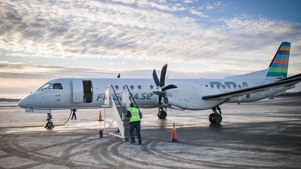 Ett flygplan som står på landningsplattan på Umeå flygplats. En flygplatsanställd håller på att ansluta trappan för att passagerare ska kunna gå ur planet.