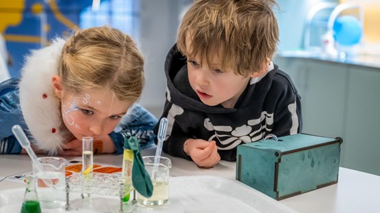 Två barn gör häxan Agata Densitatas spannande kemiexperiment på Curiosum