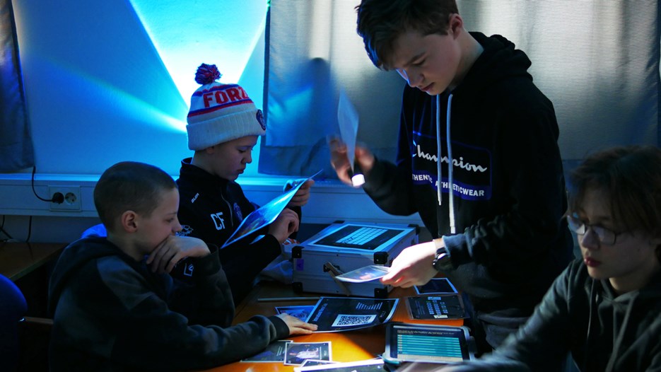 Fyra pojkar undersöker ledtrådar i rymningsspelet Space Escape. 