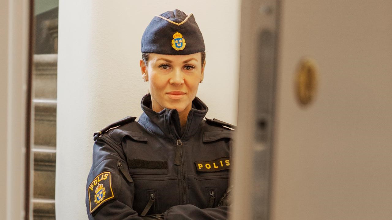 En kvinnlig polis som står bakom en dörr.