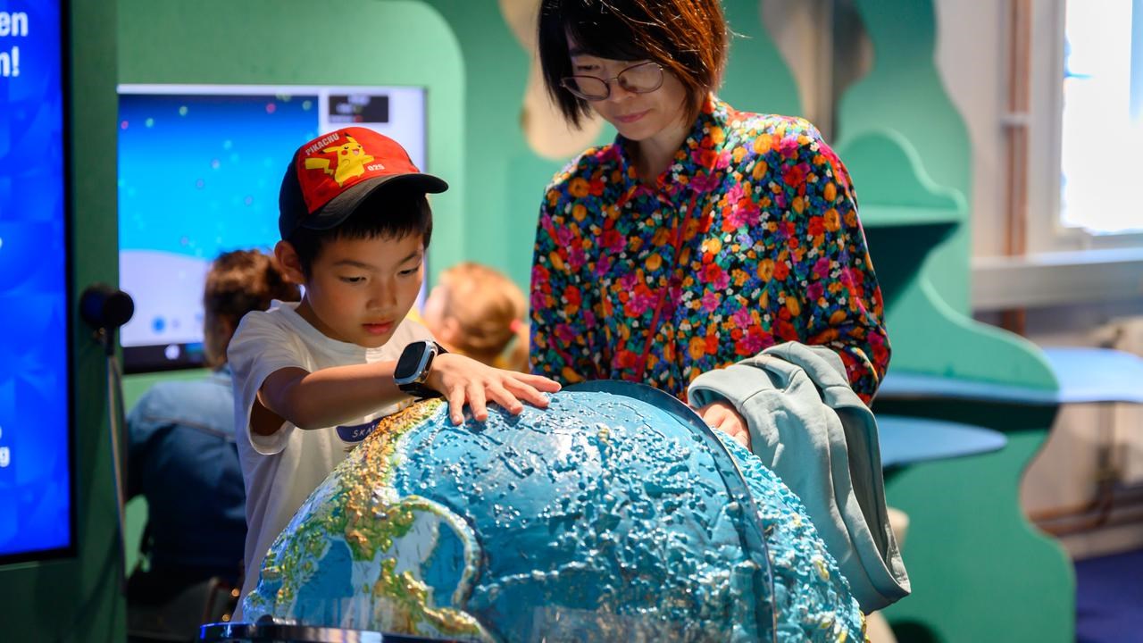 Barn och mamma utforskar jordglob i Curiosums utställning Jorden