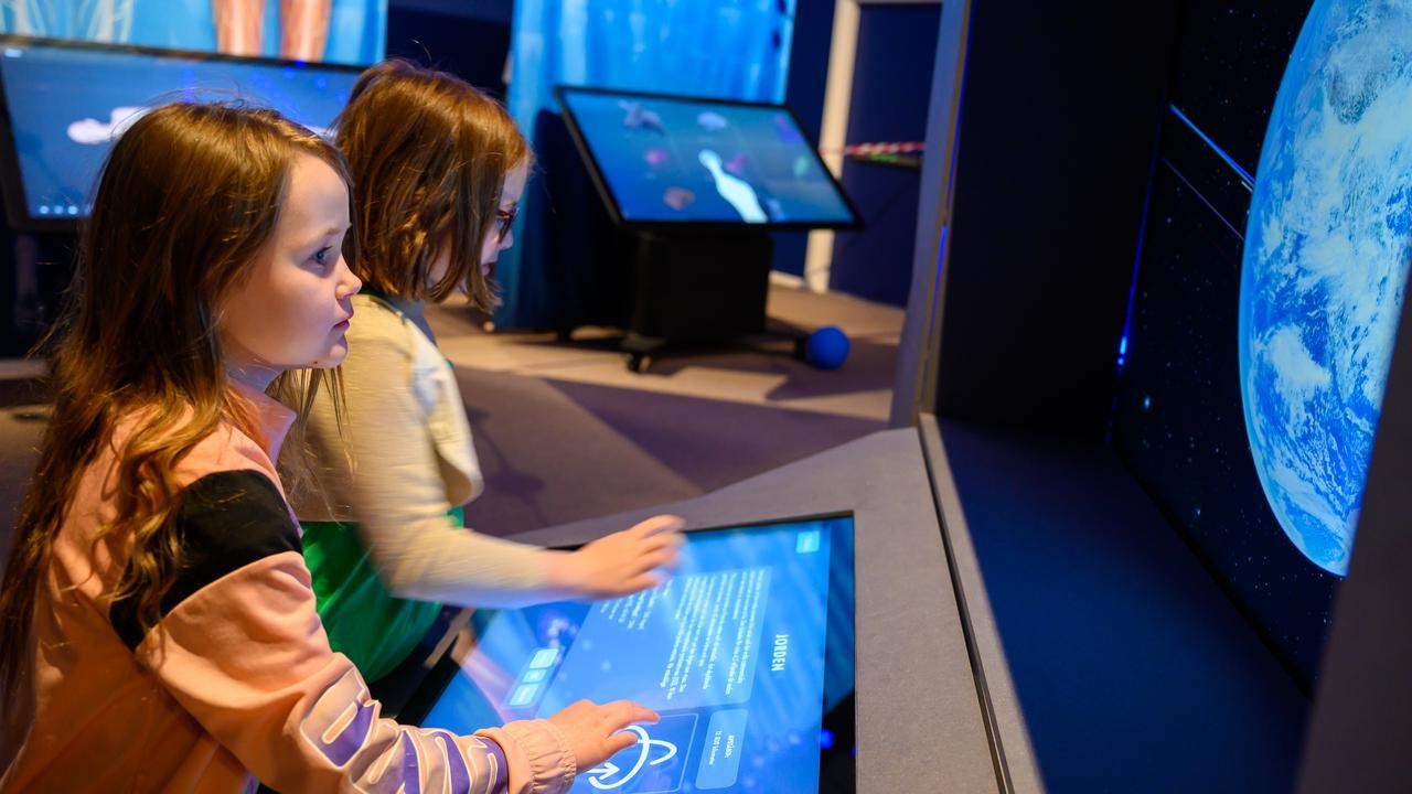 Två barn utforskar Curiosums digitala skärmar