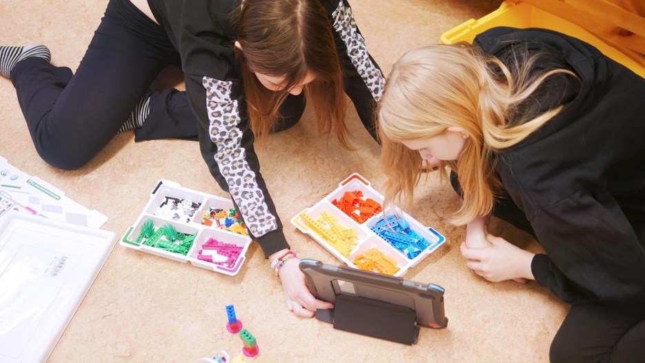 Två barn programmerar en LEGO-robot. 