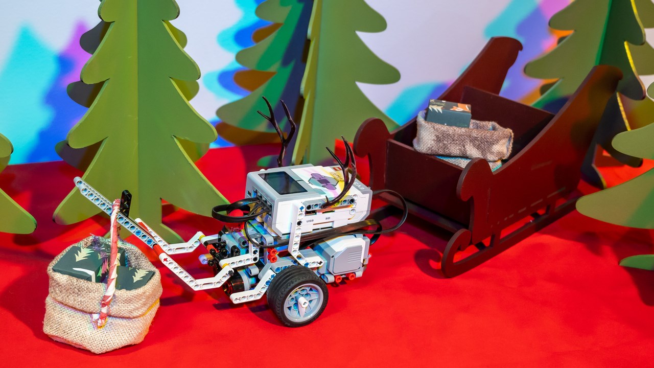 En EV3-robot med renhorn kör släde med julklappar bland granar
