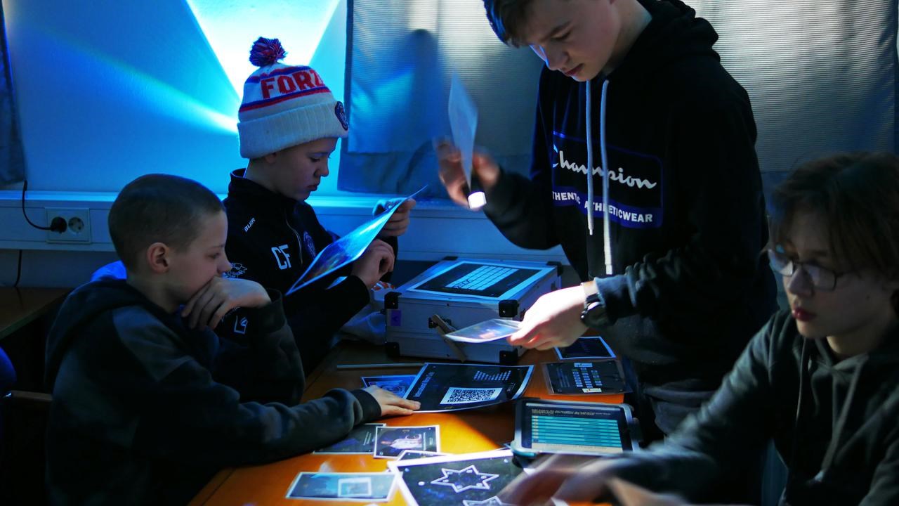 Fyra pojkar undersöker ledtrådar i rymningsspelet Space Escape. 