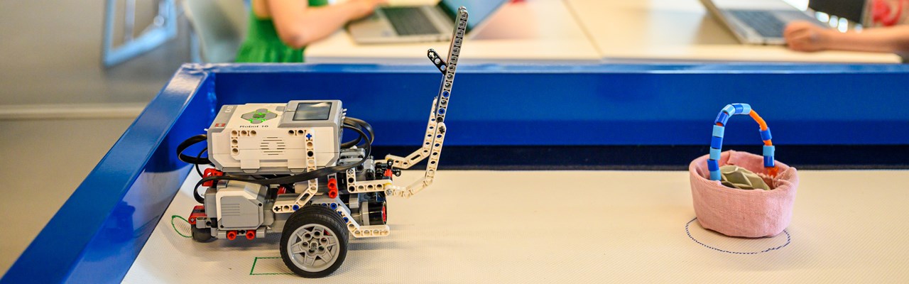 WeDo Legorobot i Curiosums tekniklabb. I bakgrunden tre barn.