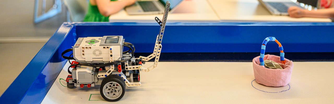 WeDo Legorobot i Curiosums tekniklabb. I bakgrunden tre barn.