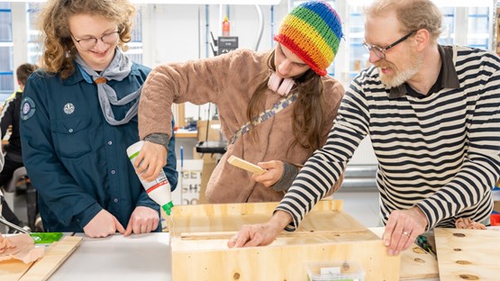Three people assemble a bat house.