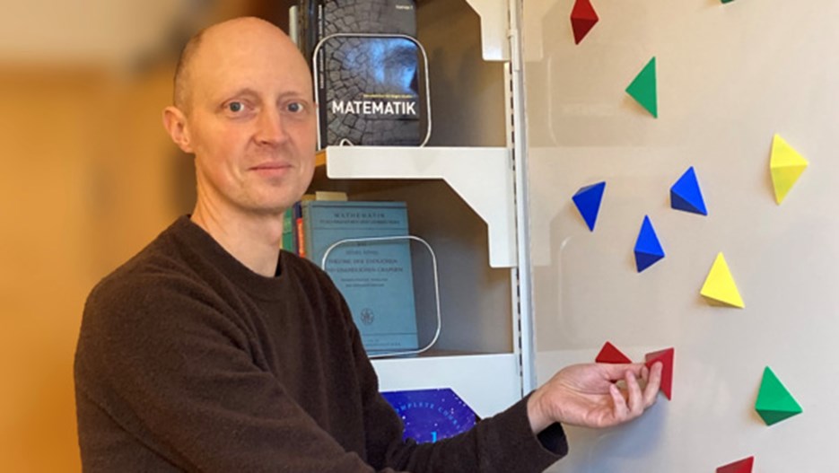 Lars-Daniel Öhman står framför en magnettavla med trekantiga magneter i olika färger