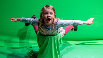 A girl is flying in front of a green screen
